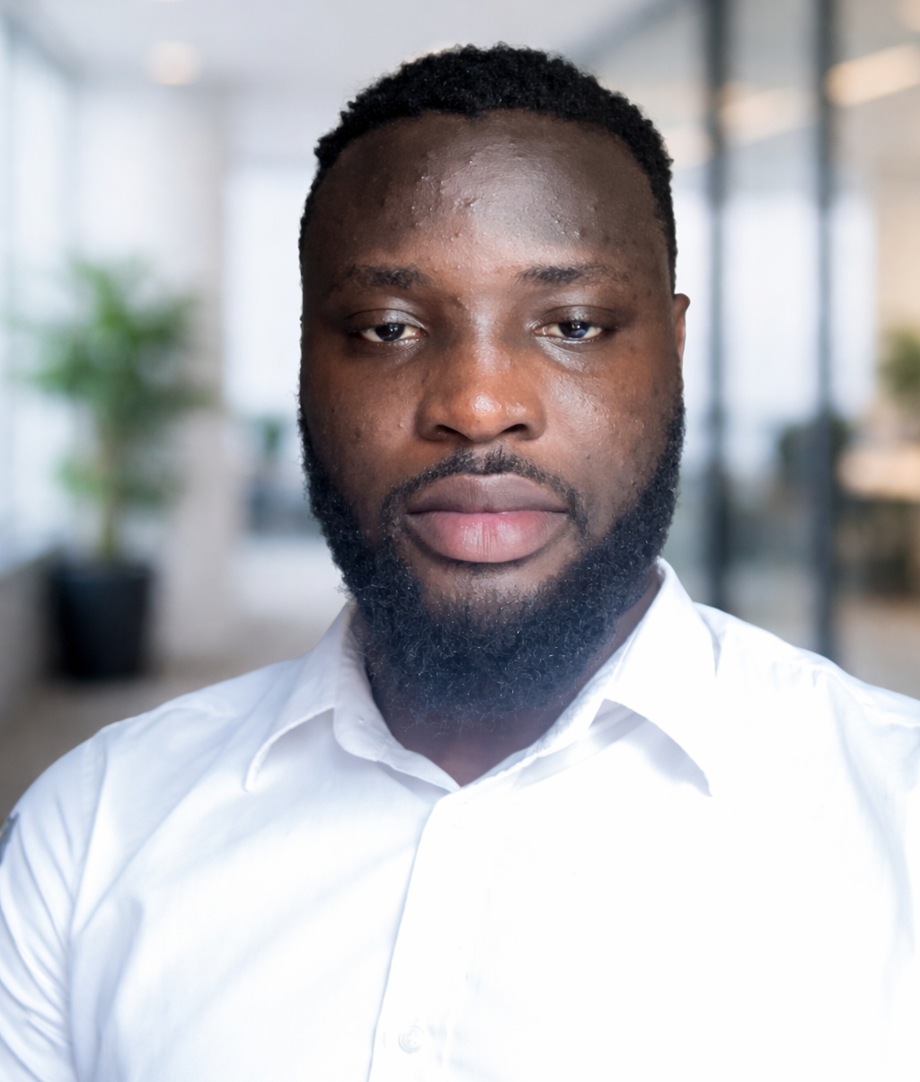Adedamola Akinpelu is wearing a white shirt, photographed in a bright, modern office with a softly blurred background.
